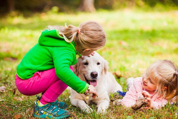 Foto lunghezza completa di bambini che giocano con il cane sull'erba