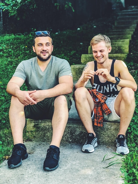 Photo full length of male friends sitting on steps