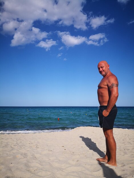 Foto lunghezza completa di un uomo sulla spiaggia contro il cielo