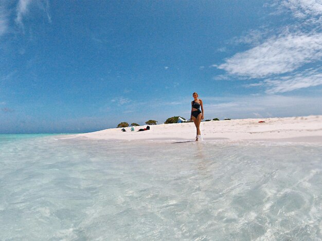 Foto lunghezza completa di un uomo sulla spiaggia contro il cielo