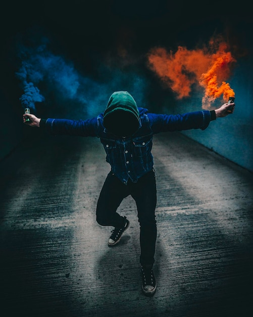 Full length of man holding distress flares against black background