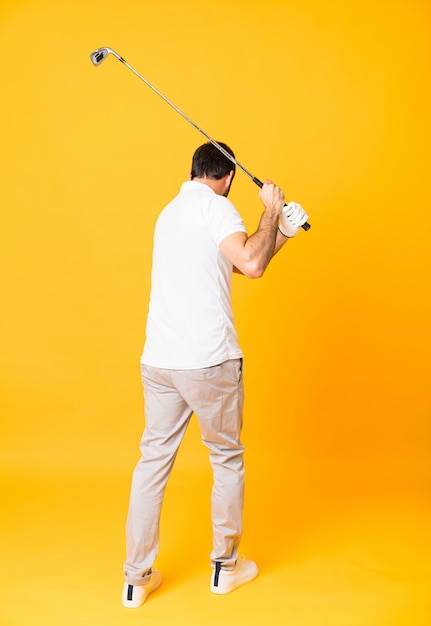 Full length  of man over isolated yellow wall playing golf