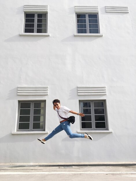 Full length of man jumping against building