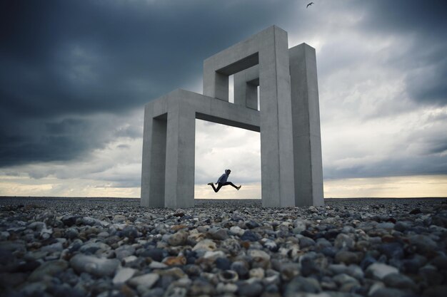 Foto lunghezza completa di un uomo che salta contro una struttura costruita e il cielo
