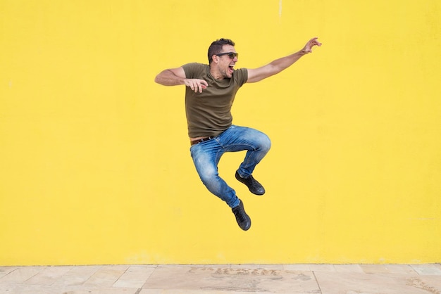 Photo full length of man jumping against yellow wall