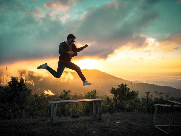 Photo full length of man jumping over field against sky during sunset