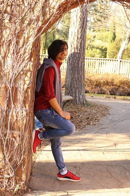 Full length of man leaning on tree trunk at park