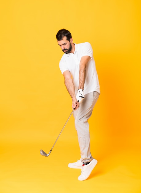 Full length  a man playing golf over isolated yellow wall