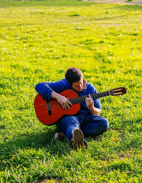 Photo full length of man playing guitar on field