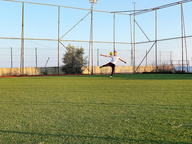 Foto lunghezza intera di un uomo che gioca a calcio sul campo