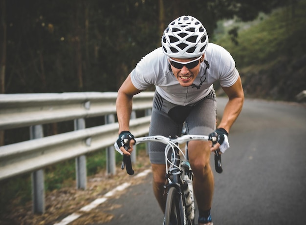 full length of man riding bicycle on road by railing