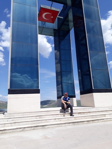 Full length of man sitting on steps at city against sky