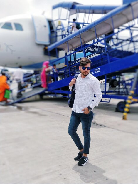 Photo full length of man standing against airplane