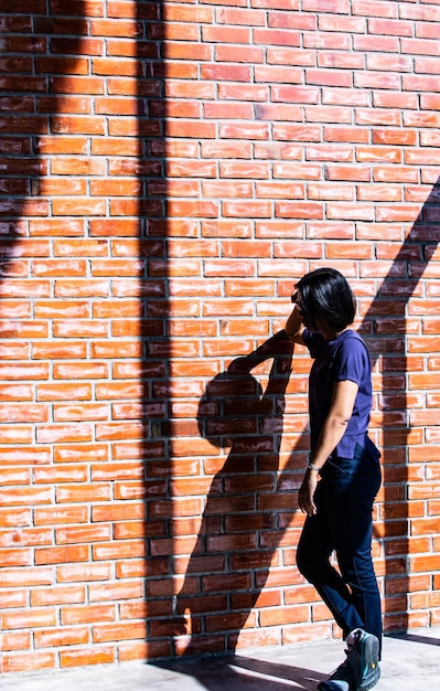 Foto lunghezza intera di un uomo in piedi contro un muro di mattoni