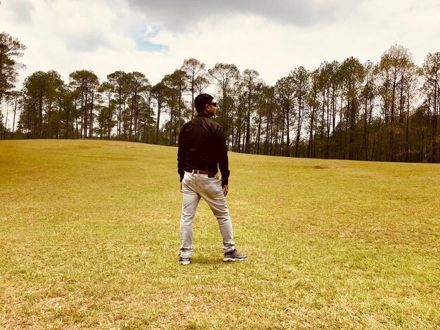 Photo full length of man standing on field against trees