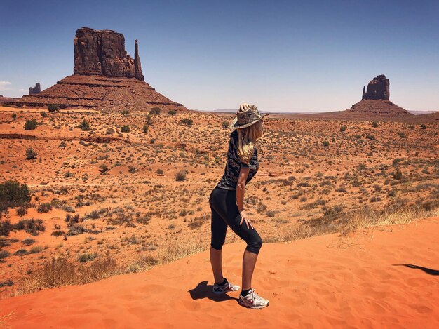 Full length of man standing on rock formation against clear sky