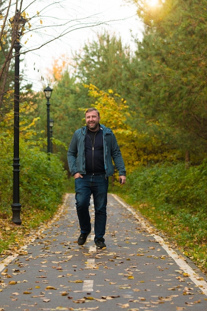 Foto lunghezza intera di un uomo che cammina su una strada stretta durante l'autunno