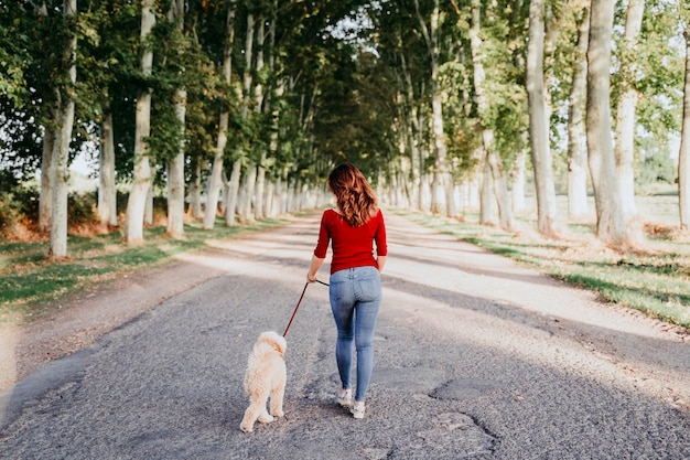 Foto lunghezza completa di un uomo che cammina con il cane sulla strada