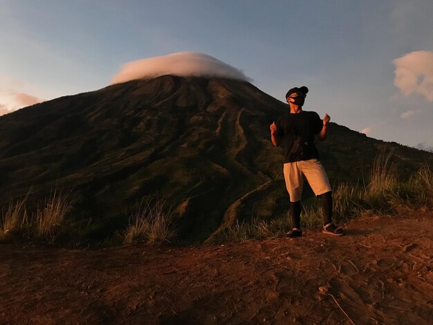 Foto lunghezza completa di un uomo che indossa una maschera in piedi contro la montagna