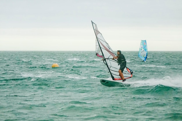 海でウィンドサーフィンをする全身長の男