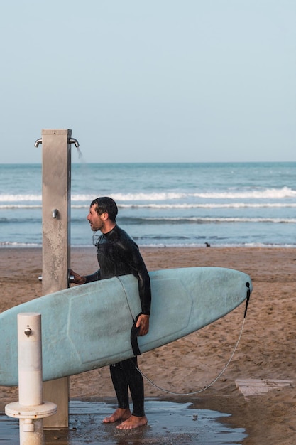 full length of man with surfboard on beach against sky