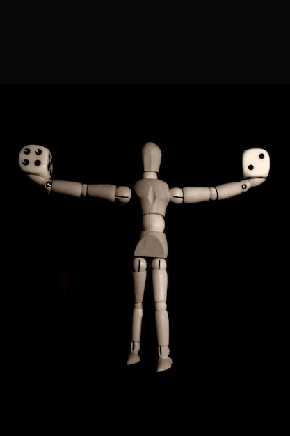 Full length of a mannequin holding dices over black background