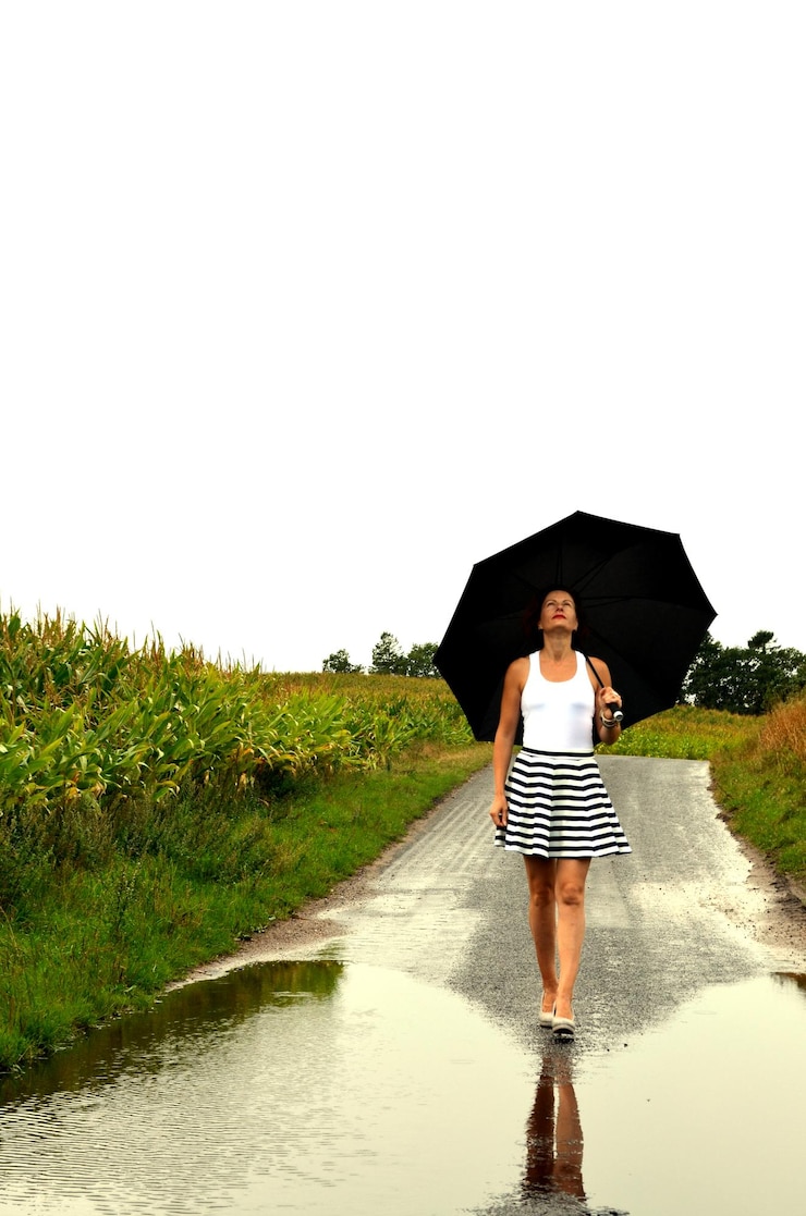 Photo full length of mature woman with umbrella walking on road against clear sky during rainy season