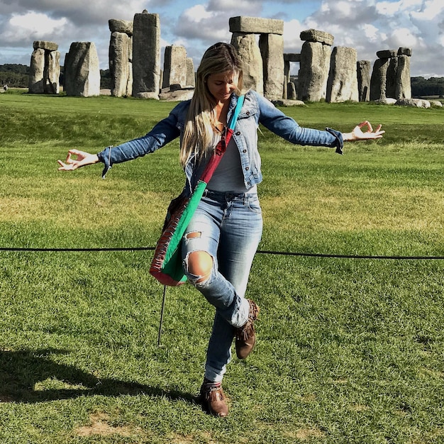 Photo full length of mid adult woman meditating against stonehenge