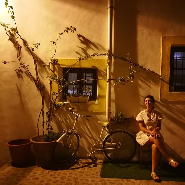 Full length of mid adult woman sitting against wall at night