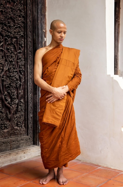 Full length of monk wearing traditional clothing while standing against building