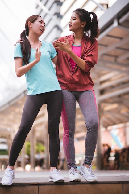 Full length of mother and daughter wearing sports clothing standing in city