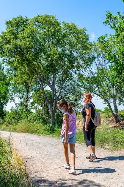 Foto lunghezza completa di madre e figlia che camminano sulla strada contro gli alberi