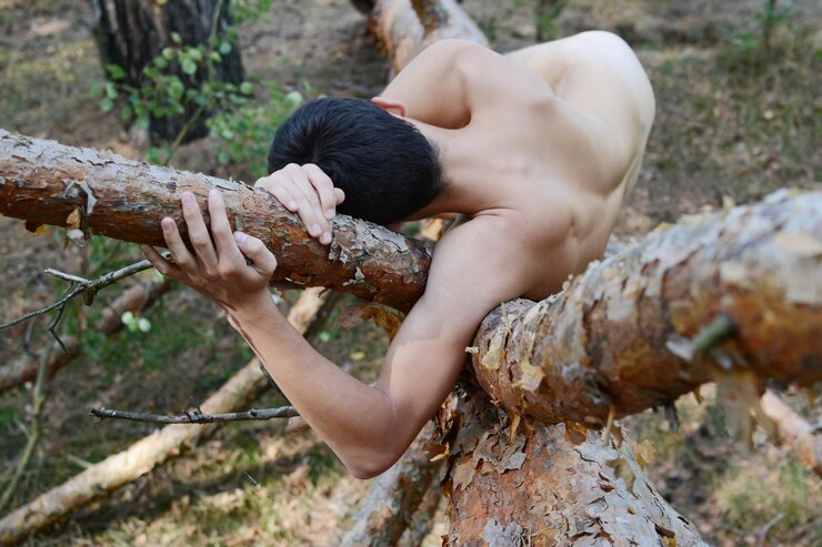 Photo full length of naked man lying on dead tree