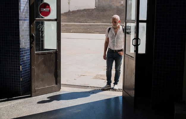 写真 晴れた日に公共の駅の入り口に立っている男の全長