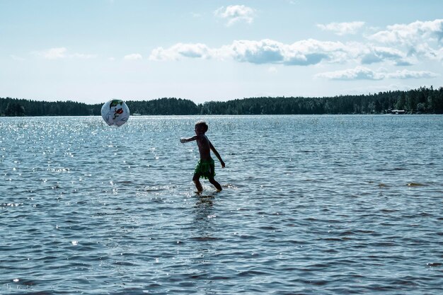 Фото Полная длина мальчика на озере на небе