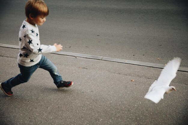 写真 都市の道路で走っている男の子の全長
