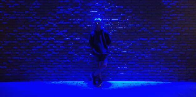 Фото Полная длина мальчика, стоящего на освещенной стене.
