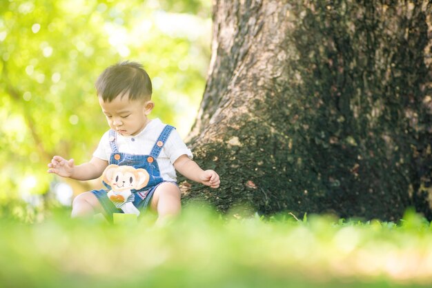 写真 木の幹に座っている可愛い赤ちゃんの全長