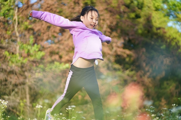 写真 野花の畑でジャンプする女の子の全長