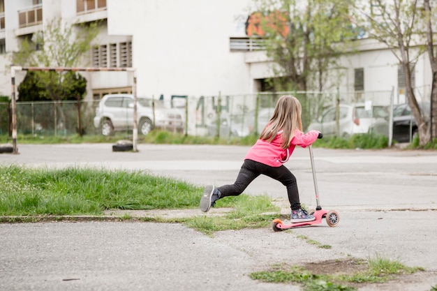 Фото Полная длина девушки, едущей на скутере в городе.