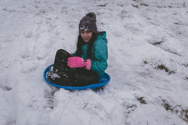 写真 雪の中のボブスレードに座っている女の子の全長