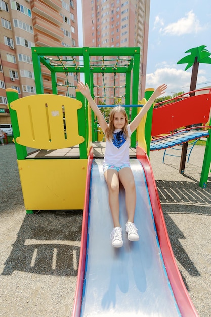 Фото Полная длина девушки, сидящей на горке на игровой площадке