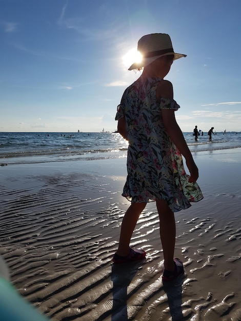 Фото Полная длина девушки, стоящей на пляже.