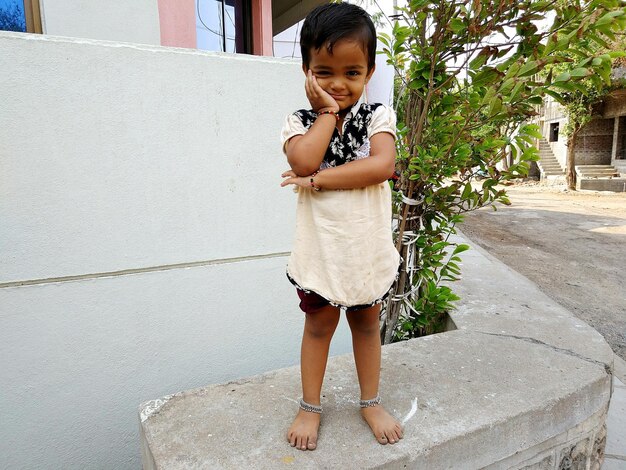 写真 壁に立っている幸せな女の子の全長