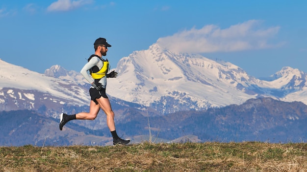 写真 空に照らして雪に覆われた山でスケートボードをしている男の全長