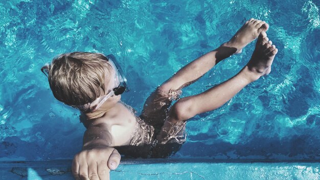 Фото Полная длина мальчика без рубашки, плавающего в бассейне
