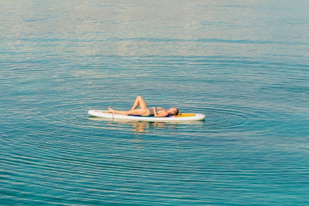 写真 海のサーフボードに横たわっている女性の全長