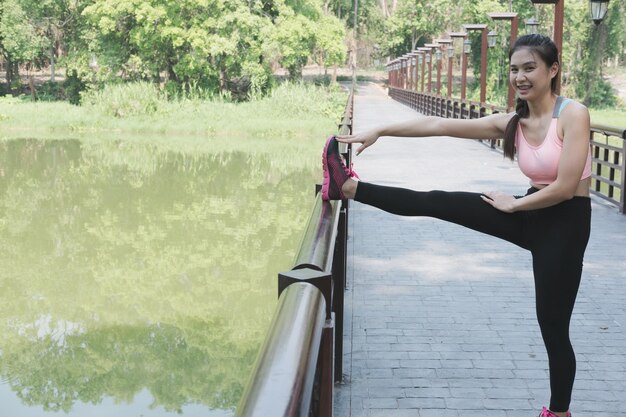 写真 木の向こうの湖でサングラスをかぶった若い女性の全長