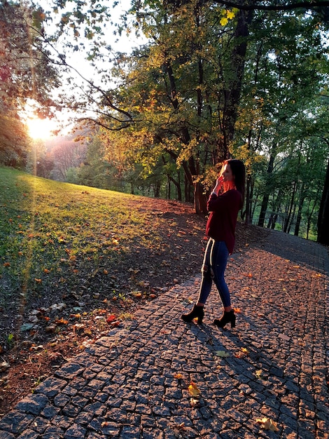 写真 歩道のフィールドに立っている若い女性の全長