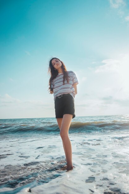 写真 浜辺に立っている若い女性の全長